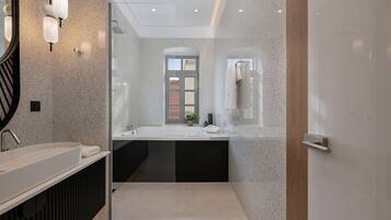A modern bathroom with a large sink, a mirror, and a shower area.