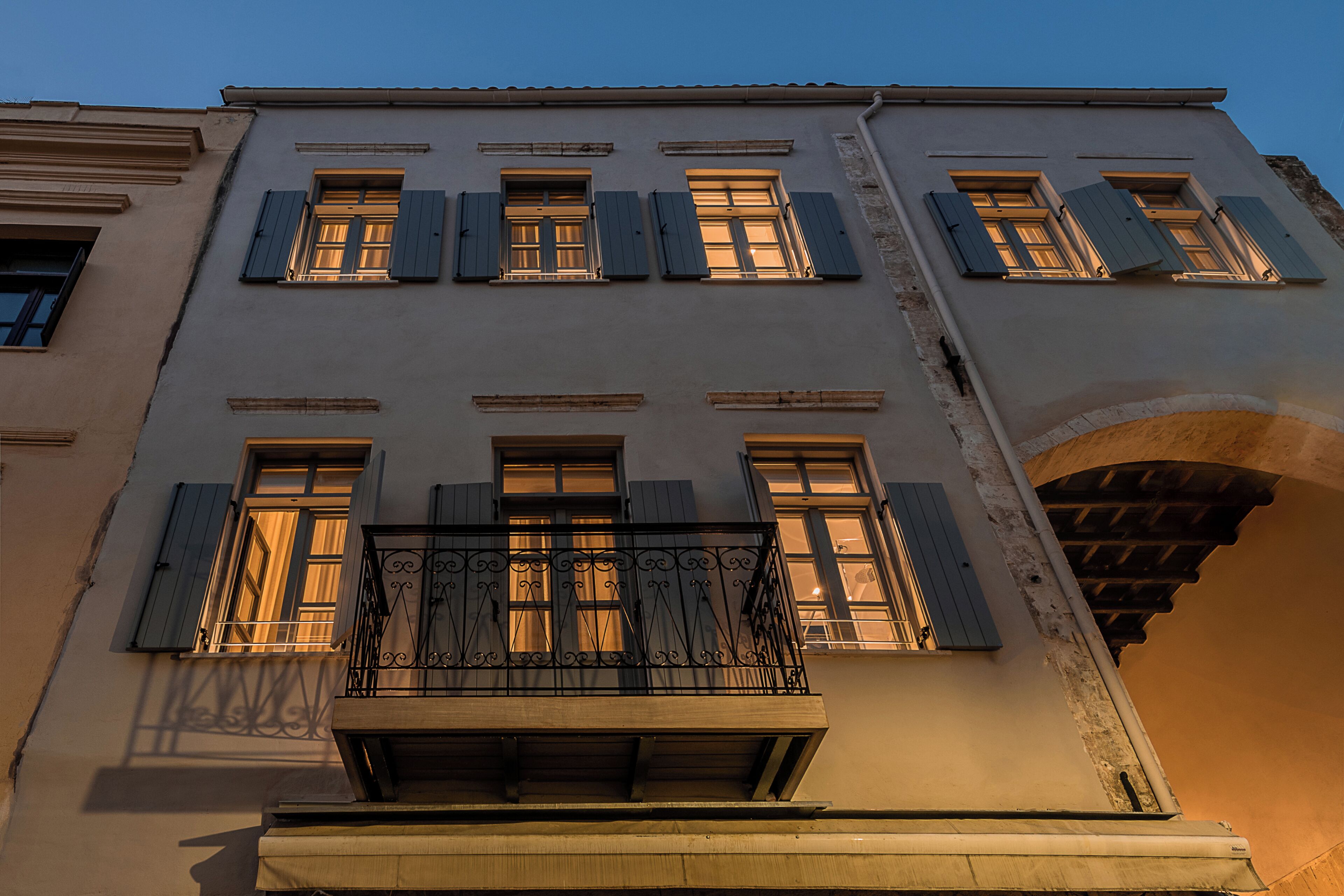A building with multiple windows, a balcony with wrought iron railings, and a stone archway.