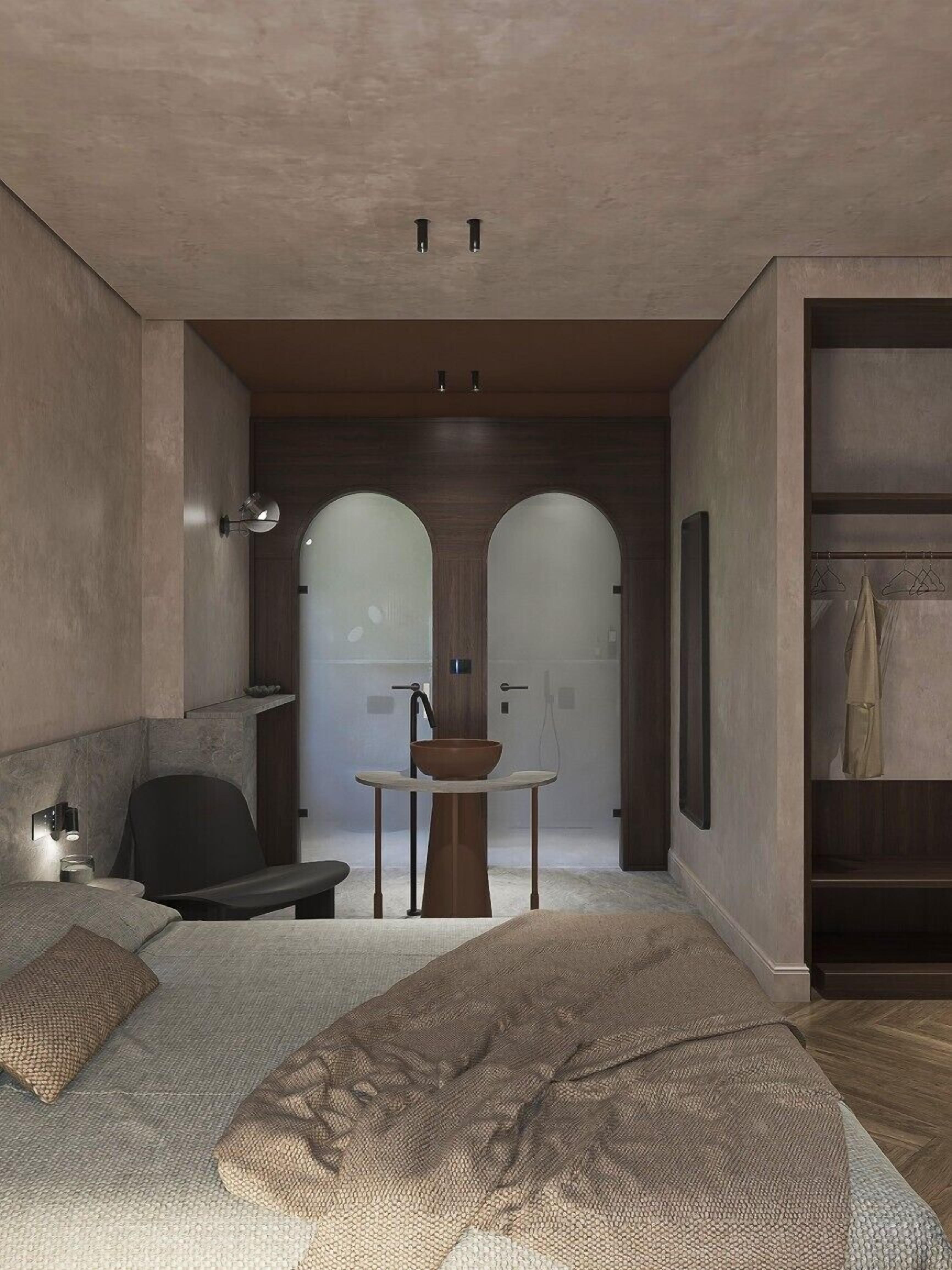 A modern bedroom with a bed, a small table with a bowl, a chair, and a wardrobe.