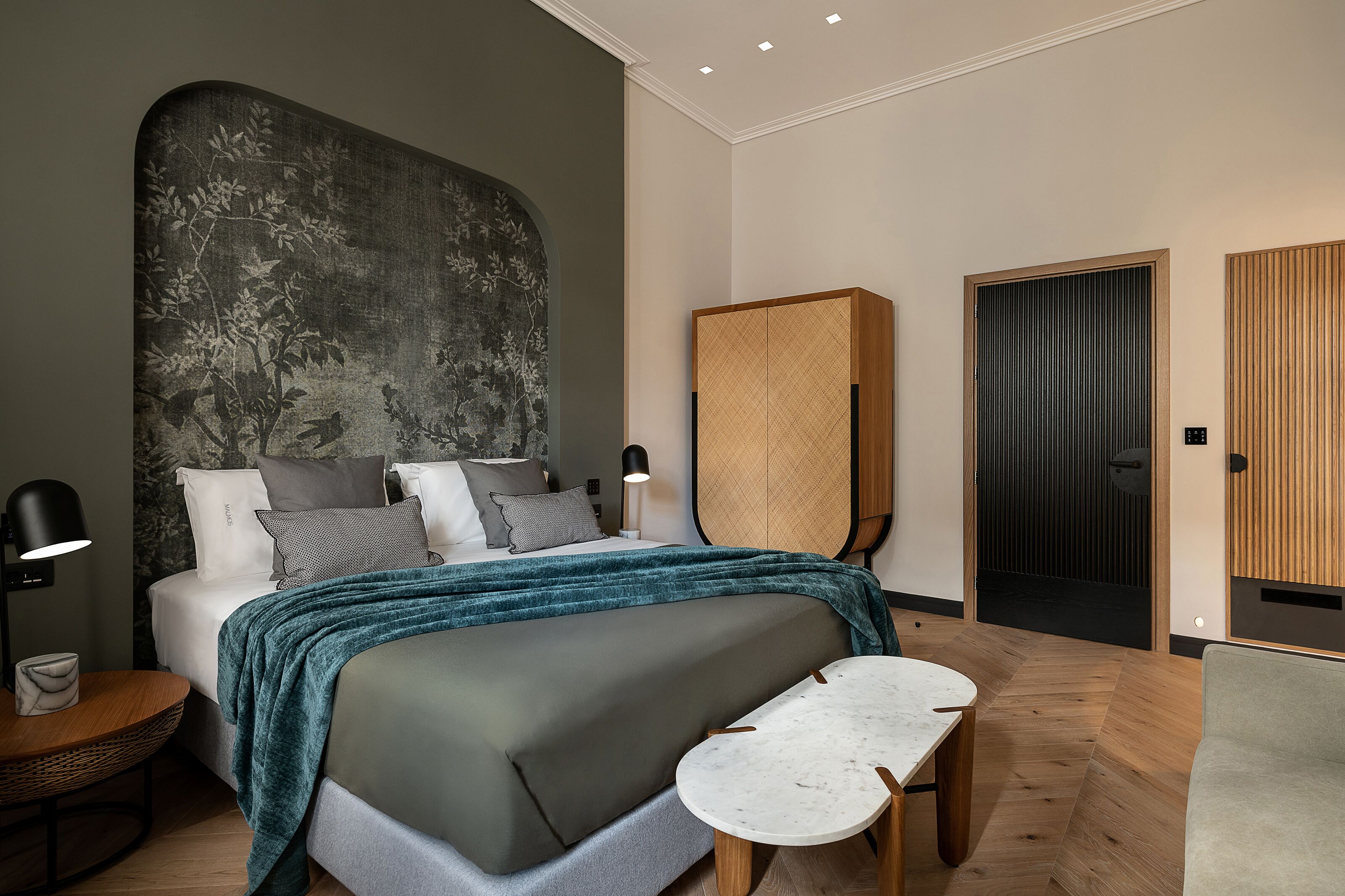 A modern bedroom with a large bed, bedside tables, a wardrobe, and a door.