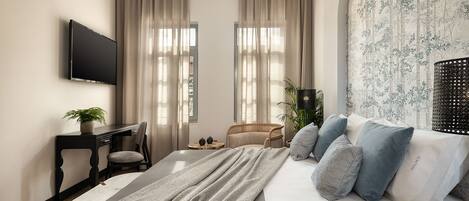 Une chambre à coucher moderne avec un lit, un bureau, une chaise et un téléviseur fixé au mur.
