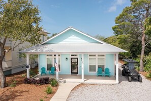 A small, light blue house with a porch, numbered 82, and a black ATV parked in front. - Aqua Waters - Newly Updated Vacation Home with Golf Cart, Private Pool + Cabana! (Destin)