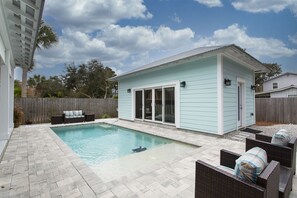 A backyard with a swimming pool, a covered patio area, and outdoor furniture. - Aqua Waters - Newly Updated Vacation Home with Golf Cart, Private Pool + Cabana! (Destin)