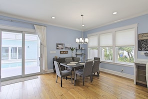 A dining area with a table and chairs, a chandelier, and a view of the outside.
