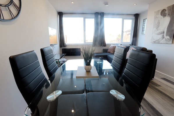 A modern conference room with a glass table, black leather chairs, and a sofa.