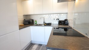 A modern kitchen with white cabinets, a black countertop, a built-in stove, a sink, and a toaster. - Interchange14 - NEC Airport Interchange (Birmingham)