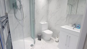 A modern bathroom with a glass-enclosed shower, a toilet, and a sink with toiletries. - Interchange14 - NEC Airport Interchange (Birmingham)