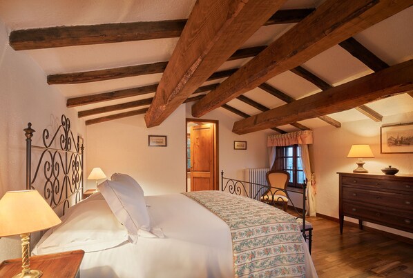 A bedroom with a wooden ceiling, a bed with a patterned bedspread, a nightstand with a lamp, a dresser, and a chair. - HAMLET THE POET - CANOPÉE HOUSE (Umbria)