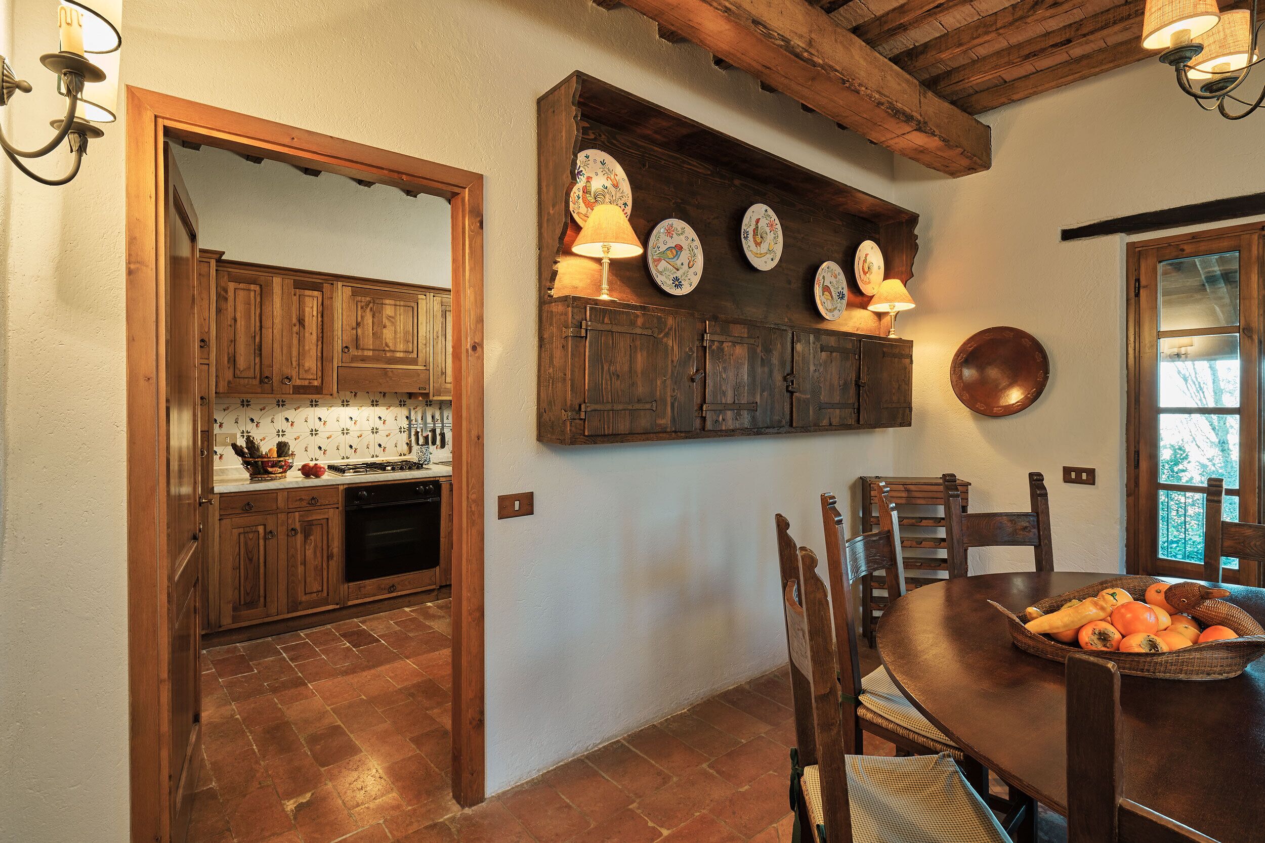 Una cocina rústica con armarios de madera, una mesa de comedor con sillas y un frutero.