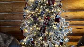 A Christmas tree with lights and ornaments in a log cabin interior.