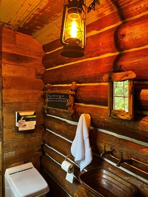 A rustic cabin interior with a wooden toilet, a sink, a lantern, and a chalkboard with a message. - Trappers Cabin, Tiny home, Romantic get away (Cocolalla)