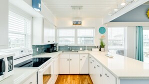 Una cocina moderna con armarios blancos, una estufa negra y una pared de acento azul.
