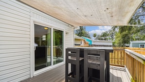A covered patio with a wooden deck, a sliding glass door, and a view of neighboring houses.