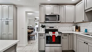 A modern kitchen with stainless steel appliances, white cabinetry, and a tiled backsplash.