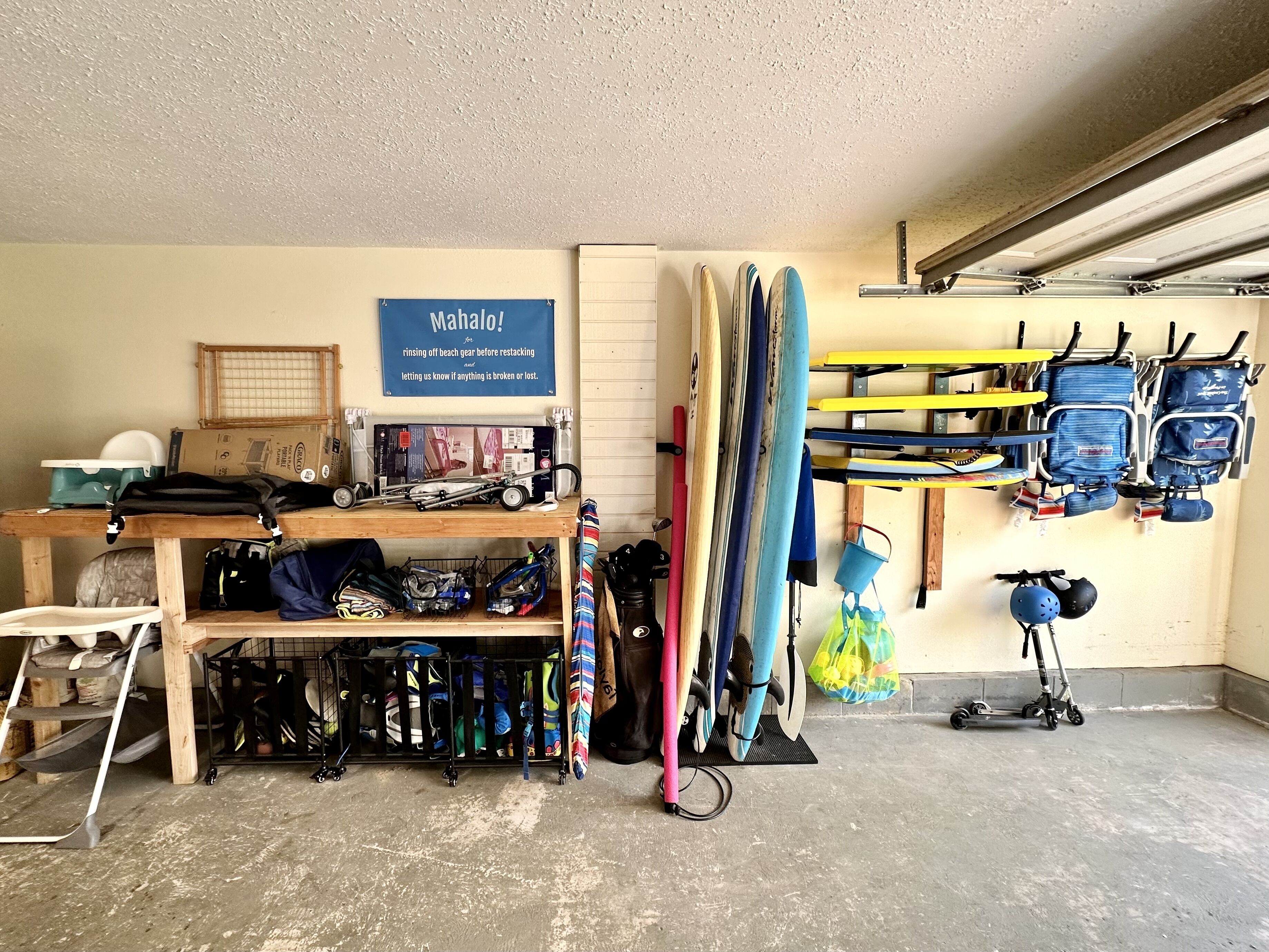 A garage with various beach gear, including surfboards and beach chairs, organized on shelves and racks.