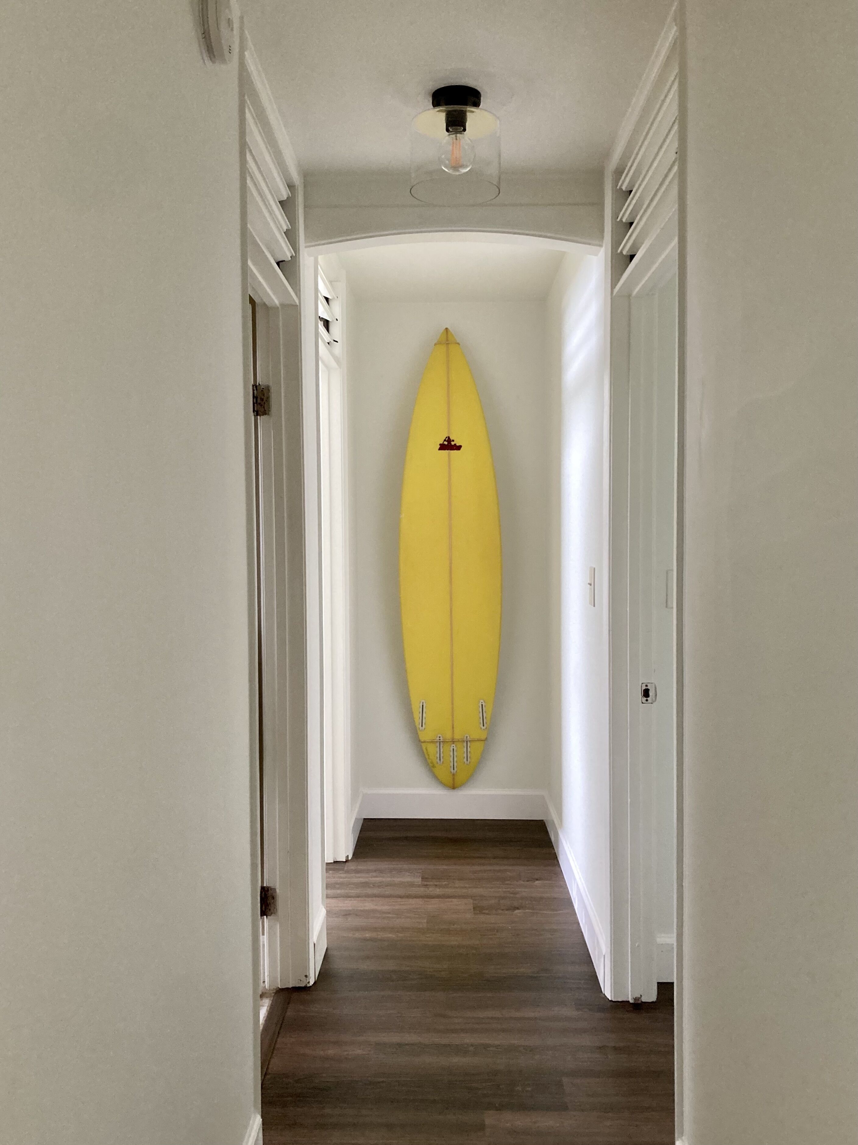A hallway with a yellow surfboard mounted on the wall.