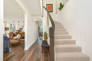 A staircase with a patterned carpet and a wooden bench at the bottom. - Breezy + Spacious 3/2 Home with Bali Hai View + Hot Tub (Princeville)