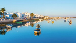 A marina with boats, a clear sky, and buildings along the waterfront. - Quinta Velha Apartamento T1 Piscina e A C (Tavira)