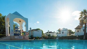 A swimming pool with a diving platform and a lifebuoy, surrounded by buildings and clear skies. - Quinta Velha Apartamento T1 Piscina e A C (Tavira)