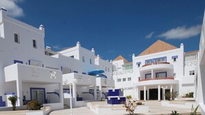 A modern hotel with white and blue architecture, multiple balconies, and a courtyard. - Quinta Velha Apartamento T1 Piscina e A C (Tavira)