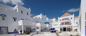 Ein modernes Hotel mit weißer und blauer Architektur, mehreren Balkonen und einem Innenhof.