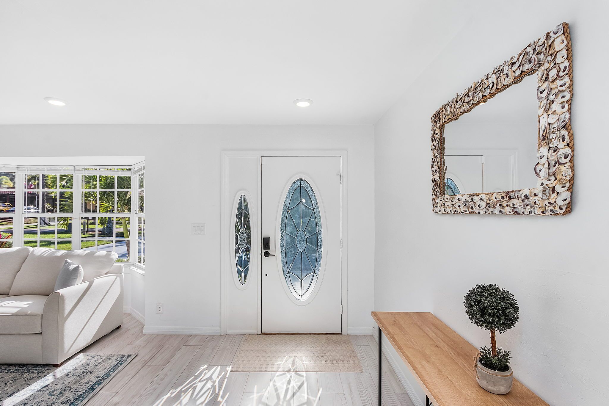 Ein modernes Interieur mit einer weißen Tür, einem runden Spiegel und einem Blumentopf.