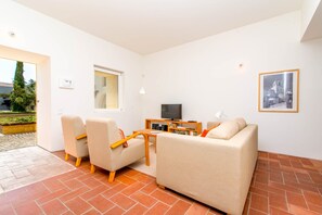 Ein modernes Wohnzimmer mit einer Couch, Sesseln, einem Fernseher und einem kleinen Tisch.