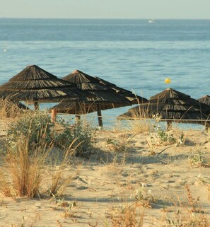 Ein Strand mit Reetdachschirmen und Blick aufs Meer.