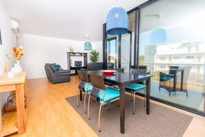 Ein modernes Wohnzimmer mit Esstisch, Stühlen, einer Couch und einem Fernseher.