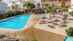 Et resort med swimmingpool, liggestole og en træterrasse.