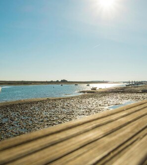 Eine Küstenlandschaft mit Sandstrand, ruhigem Wasser und Booten.