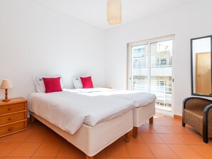 Ein Schlafzimmer mit Bett, Nachttisch, Stuhl und einer Schiebetür zum Außenbereich.