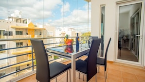 A balcony with a glass table, two chairs, and a fruit bowl. - Pegada Apartamento T3 Luxo (Tavira)