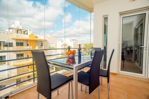 A balcony with a glass table, two chairs, and a fruit bowl. - Pegada Apartamento T3 Luxo (Tavira)