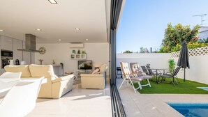 Ein modernes Wohnzimmer mit Sofa, Sesseln, Fernseher und Küchenzeile.