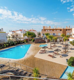 Ein Poolbereich eines Resorts mit Holzdeck, Liegestühlen und Sonnenschirmen.