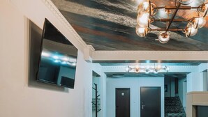 A modern lounge area with a sofa set, a flat-screen TV, and a staircase leading to an upper level. - Suru Hotel & Restaurant (Busteni)