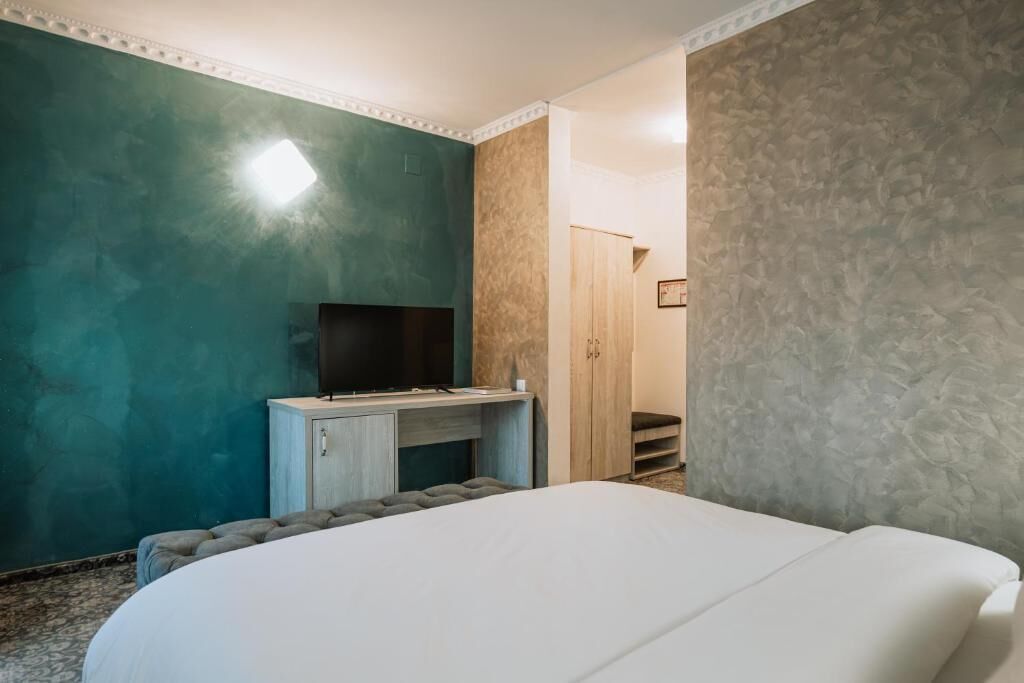 Un dormitorio con cama, escritorio, televisor y armario.