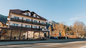 A multi-story hotel with a balcony on the second floor, a mountain backdrop, and a clear sky. - Suru Hotel & Restaurant (Busteni)