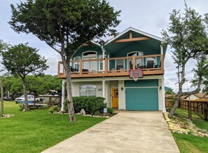 Enjoy the view from the upper-level balcony with a basketball hoop, surrounded by a lush green roof and a charming front yard.