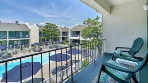 Ein Balkon mit Pool, Liegestühlen und Sonnenschirmen.