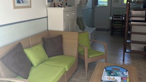 Ein Wohnzimmer mit einer Couch, Sesseln, einem Couchtisch und einer Küchenzeile im Hintergrund.