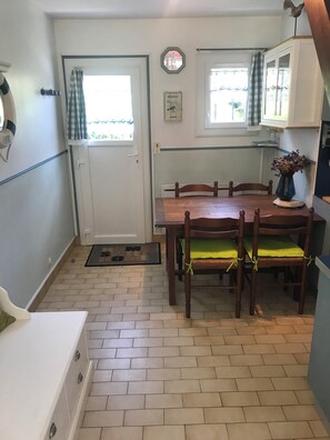 Een kleine keuken met een houten tafel, stoelen en een kast.