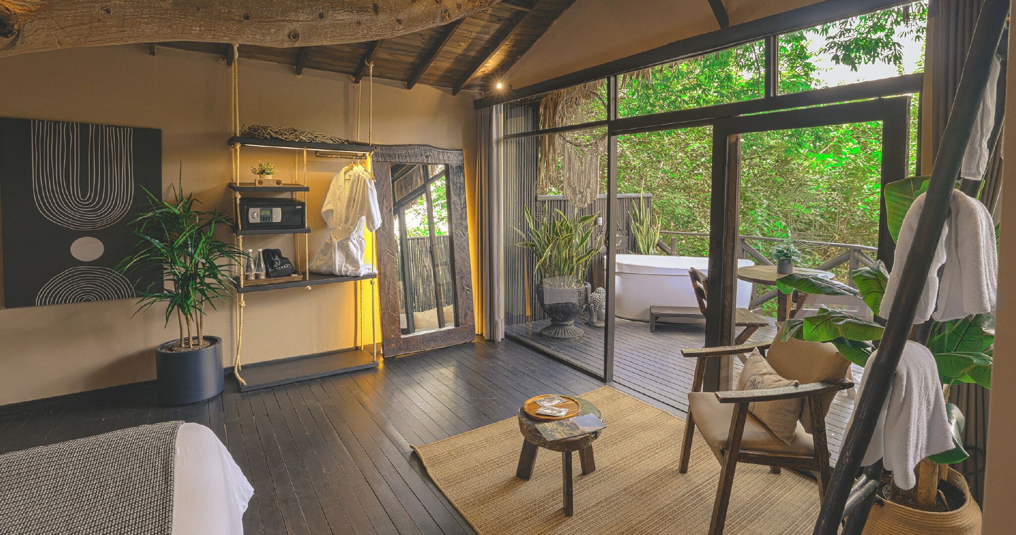 A spacious room with a large window, a wooden floor, a hanging chair, and a small table.