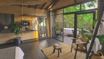 A spacious room with a large window, a wooden floor, a hanging chair, and a small table.