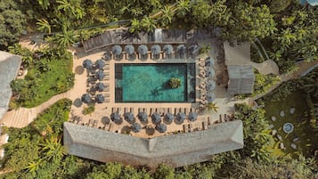 Relax by the central pool surrounded by lush greenery and palm trees.