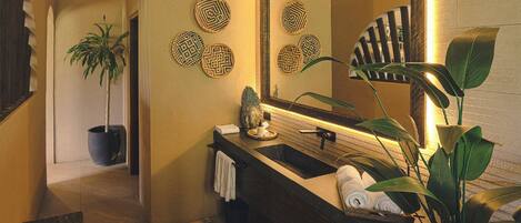 Une salle de bain moderne avec un meuble-lavabo en bois foncé, un grand miroir et des éléments décoratifs muraux en forme de motifs tissés.