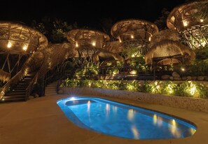 A swimming pool surrounded by wicker furniture and stairs leading to an upper level. - Casa Candela (Sopetrán)