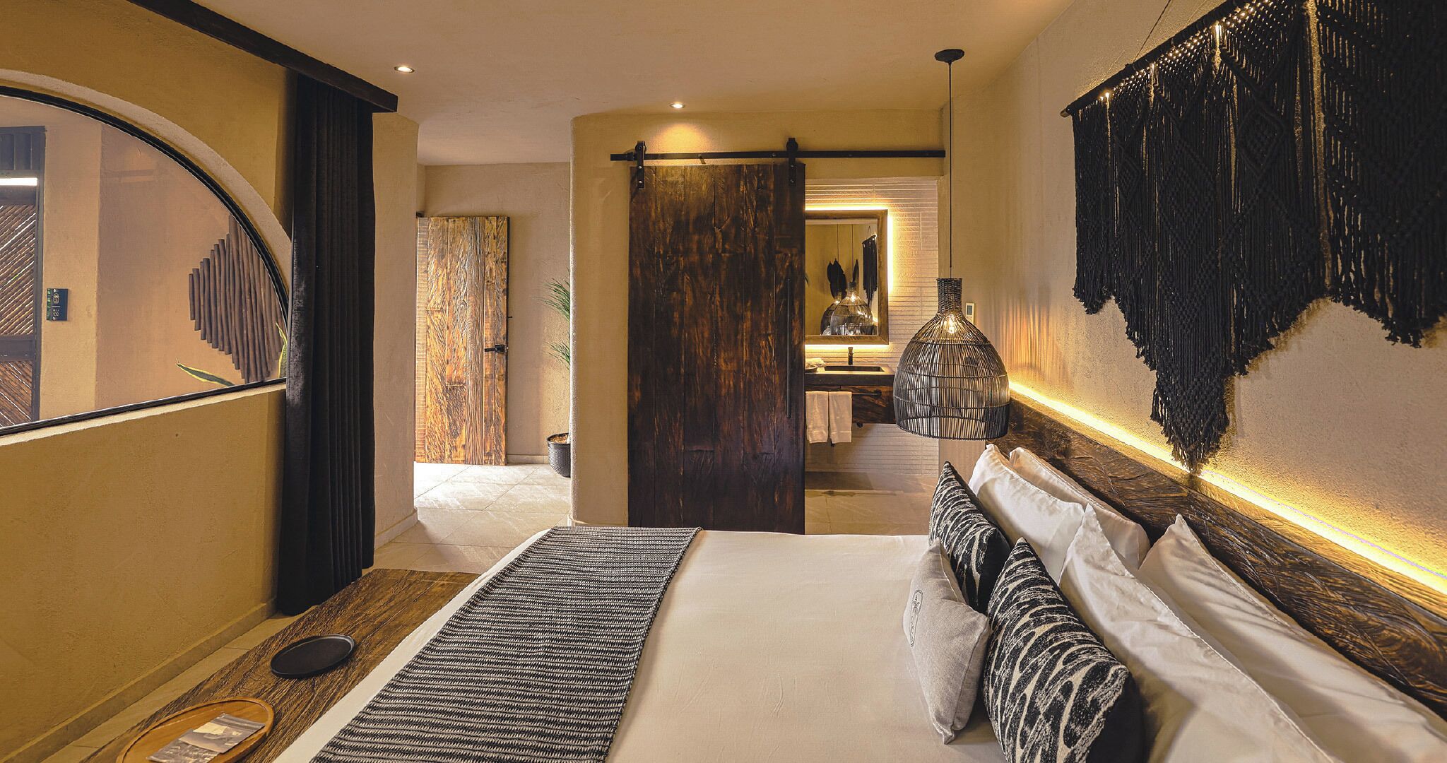 Une chambre avec un grand lit, une porte en bois foncé et un luminaire fixé au mur.