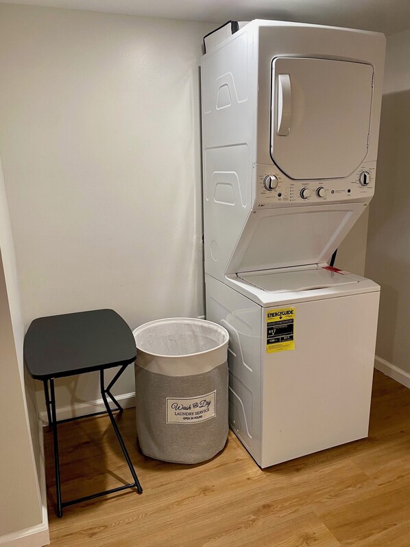 A compact washer and dryer unit with a small table and a laundry basket. - The Monrow Brownstone! (West New York)